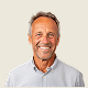 Smiling middle-aged man with gray hair and a light beard wearing a light gray collared shirt.
